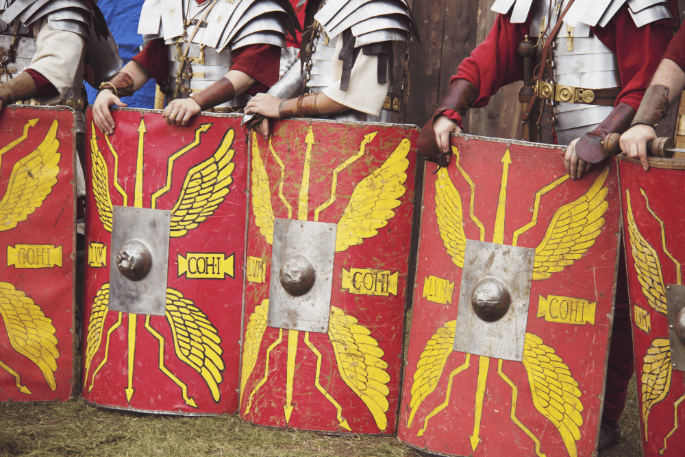 Roman legionary soldiers with their red scutum shields resting on the ground